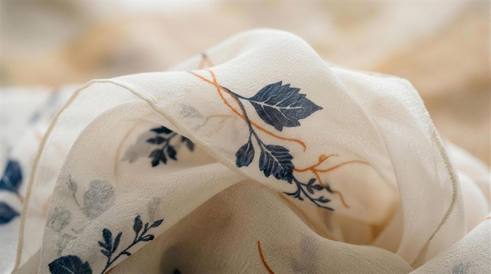 Macro of featherlight printed silk chiffon, a navy leaf and orange stem showing through the sheer folds